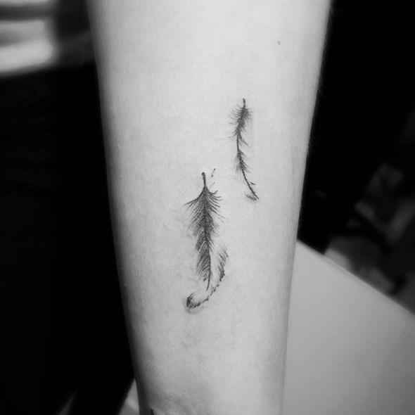 small black feather tattoo on arm