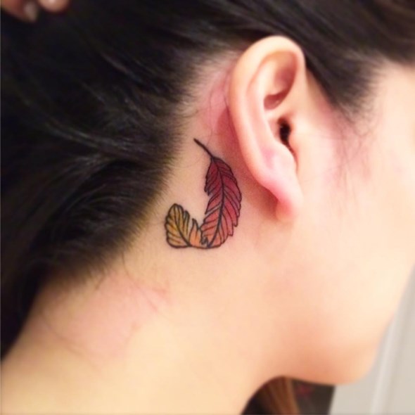 small phoenix feather tattoo behind the ear