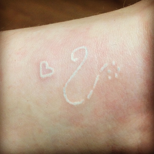 Leo and heart white ink tattoo on wrist