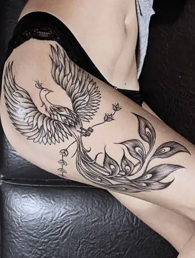 a woman's black phoenix hip tattoo